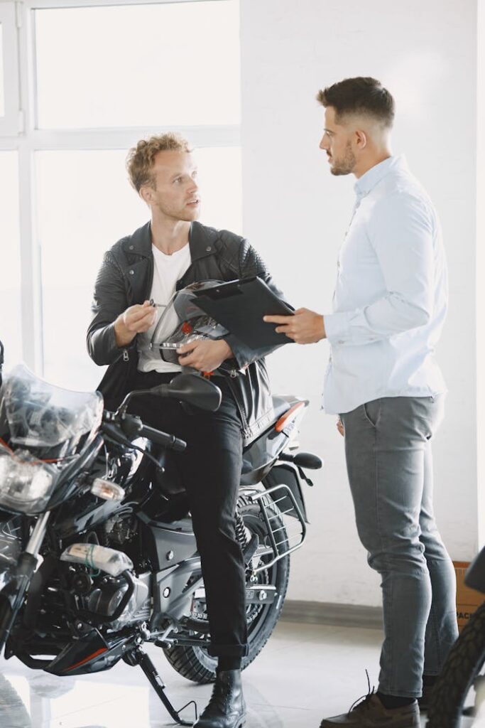 Two men discussing a motorcycle purchase inside a dealership.
