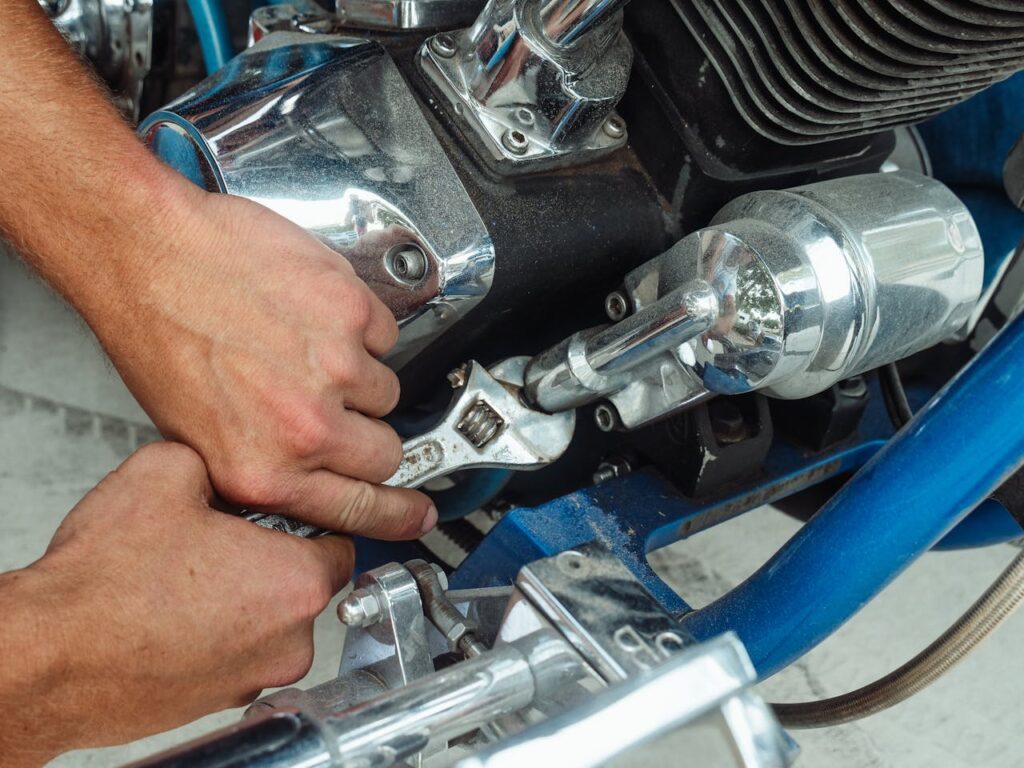 Close-up of a mechanic's hands using a wrench to repair a motorcycle engine.